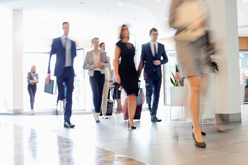A blurred crowd of business people walking into a building.