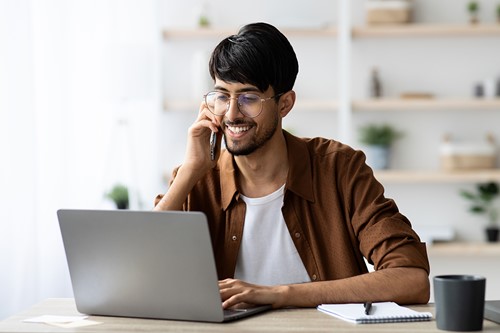 An indian customer sitting by his computer at home receiving a call about Alfa's pre-hire service.