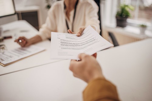 An landlord handing over a rental contract to a tenant at the office.