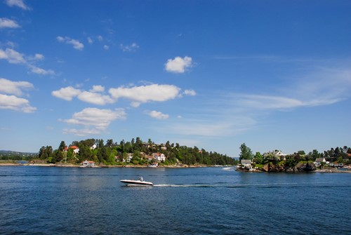 Kauniita maisemia sinisellä taivaalla ja veneellä Norjassa.