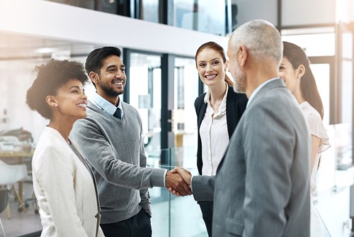 A diverse group of business people shaking hands in an office setting.