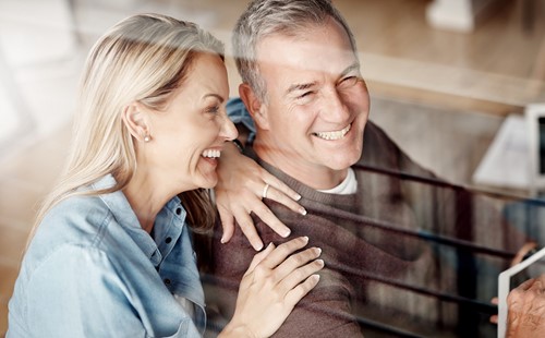 Smiling middle-aged couple sitting in their livingroom being content with their international move.