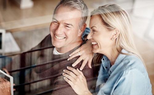 Smiling middle-aged couple sitting in their livingroom being content with their international move.