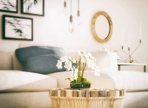 A bright livingroom interior with a small table with a vase and flowers in the foreground.