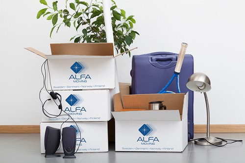 Valkoiset Alfa-muuttolaatikot sinisillä Alfa-logoilla pinossa kotitaloustavaroiden kanssa pakattavaksi ja säilytettäväksi.