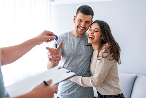 A happy couple that receives their apartment key from an Alfa consultant inside their new apartment.