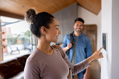 A couple moving into their apartment checking the alarm on the wall.