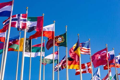 Several rows of flags from around the world towards a bright blue sky.