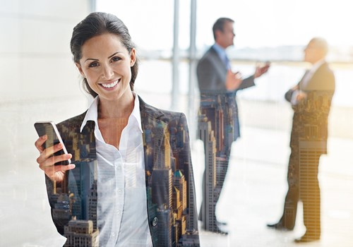 An Alfa representative holding a mobile phone staning in front of two business men in the background.