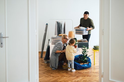 En familj på tre personer som förbereder sig för en besiktning av sitt bohag sett från dörröppningen.