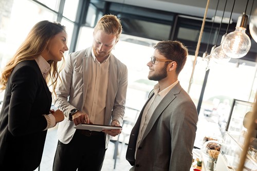 Tre personer interagerar på ett kontor och diskuterar import- och exportpriser.