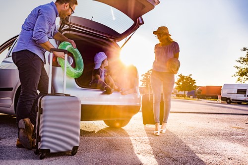 En familj på tre som lämnar sitt hem och packar sin bil med personliga tillhörigheter innan de flyttar till ett annat land.