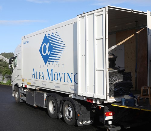 Vit Alfa-lastbil med blå Alfa-logga som levererar bohag utanför ett privatägt hus.
