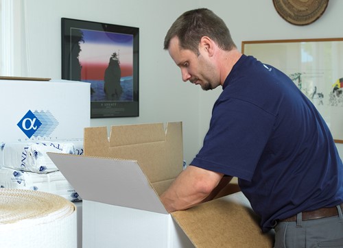 An Alfa professional packer in blue Alfa clothes packing in Alfa boxes with Alfa logo.